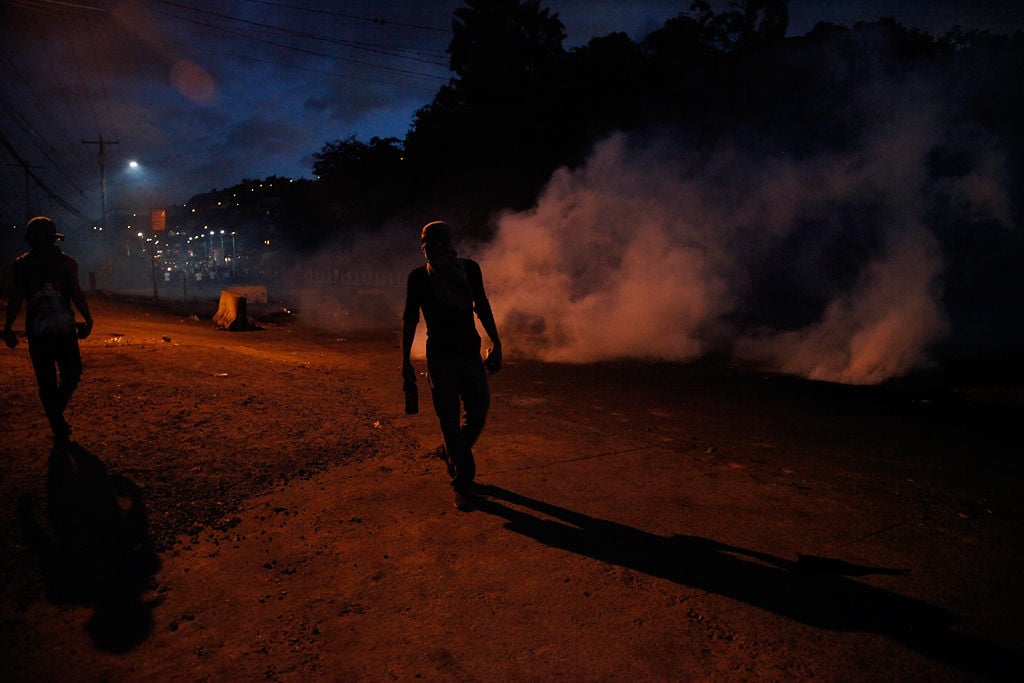 Supporters of presidential candidate Salvador Nasralla walk among tear gas